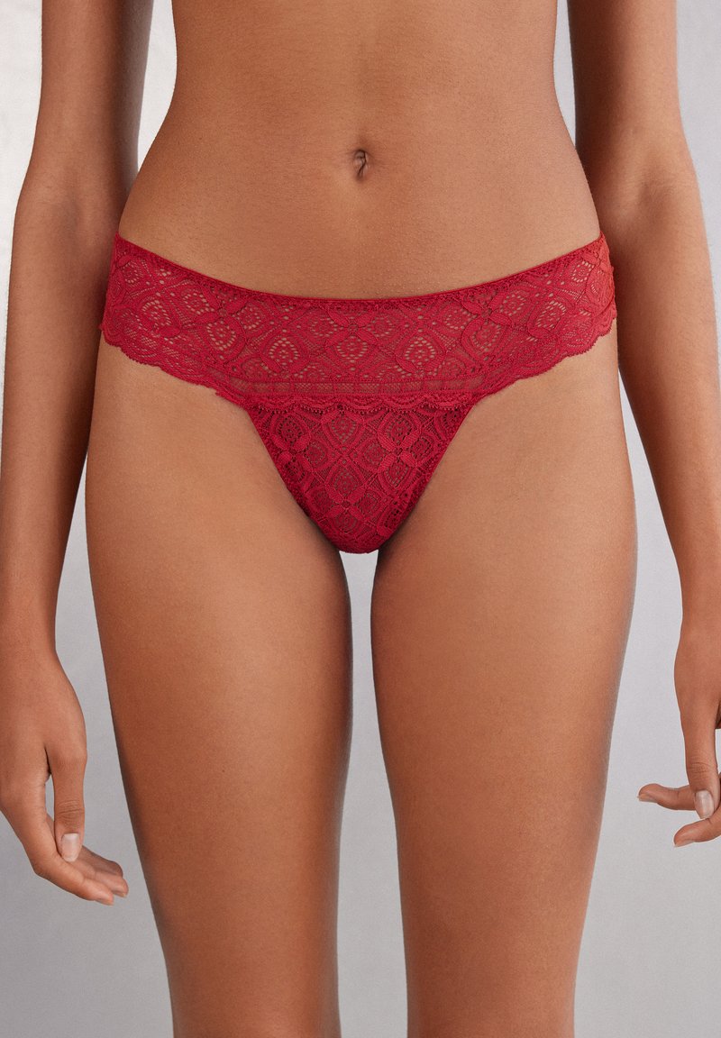Rode kantene string met een geschulpte tailleband, voorzien van een bloemmotief en een doorschijnende textuur. Ontworpen voor een minimale bedekking.