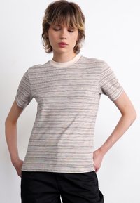 Stribet T-shirt i lys tan, med korte ærmer og rund hals med en kontrastfarvet beige kant; blødt stof med subtil tekstur.