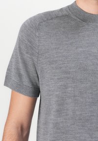 Γκρι κοντομάνικο πλεκτό t-shirt με ραμμένο λαιμόκοψη crew και διακριτή υφή, που έχει εφαρμοστή γραμμή και καθαρά ραψίματα στις ραφές.