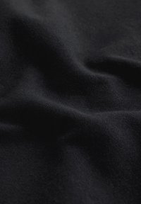 Tissu noir avec des plis doux et une surface lisse légèrement texturée remplissant le cadre.