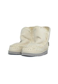 Botines de ante beige con una textura suave, que cuentan con costuras decorativas alrededor de la parte superior y una suela de goma gris.