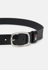 Ceinture en cuir noir avec une boucle rectangulaire en argent gravée "TOMMY JEANS" et une boucle de marque avec des accents rouges et bleus.