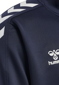 Marineblauw sportshirt met een gladde textuur, witte chevronprint op de schouder en een logo aan de voorkant.