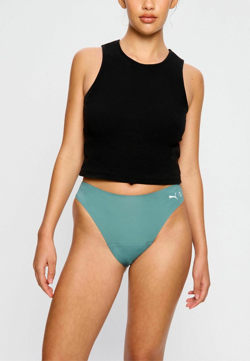 Ensemble de vêtements de sport composé d'un crop top sans manches noir et d'un bas de bikini taille haute teal avec un accent logo sur le côté.