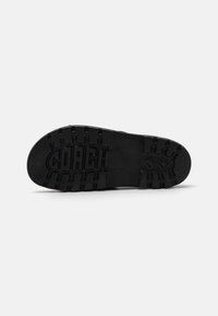 Black rubber sneaker sole with visible tread pattern. Features the brand name "COACH" embossed in large letters across the center.