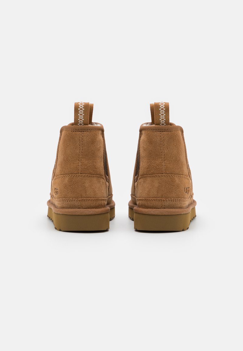 Botas de tobillo de ante marrón con un acabado texturizado, que cuentan con una suela de goma, dos lengüetas y costuras contrastantes en el tobillo.