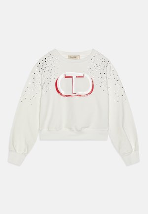 Sweat-shirt court blanc à manches longues, avec un logo rouge et des embellissements argentés sur les épaules, doté d'un ourlet et de poignets côtelés.