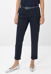 Pantaloni blu navy con design a gamba dritta, dotati di una cintura con fibbia argentata e orli arrotolati, abbinati a ballerine argentate a punta.