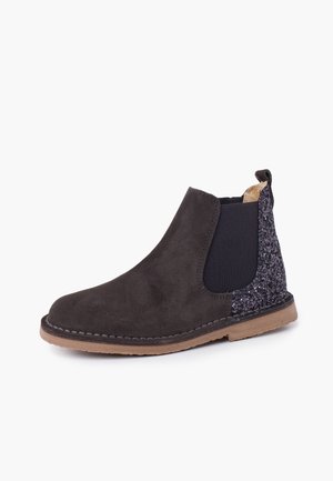 Czarne zamszowe botki Chelsea z błyszczącym tylnym panelem, elastycznymi bocznymi wstawkami, brązową podeszwą i pętelką na białym tle.