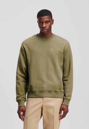 Felpa verde oliva in misto cotone, con scollatura a girocollo e polsini a costine. Piccolo logo sulla parte anteriore.