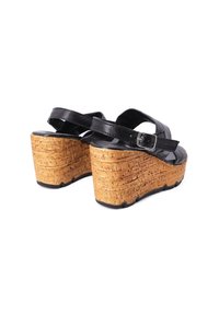 Sandali con zeppa in pelle nera, caratterizzati da una piattaforma in sughero, cinturino regolabile con fibbia e superficie texturizzata. Design con retro aperto.