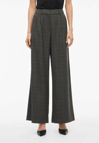 Hlače širokih nogavica u tamnosivoj boji s kariranim uzorkom u narančastim akcentima. Imaju nabore i visoki struk, izrađene su od teksturirane tkanine.