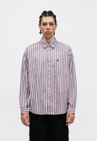 Világos lila, hosszú ujjú, gombos ing fehér függőleges csíkokkal. Kialakításában található egy zseb és gombolható gallér. Puha szövet tapintású.