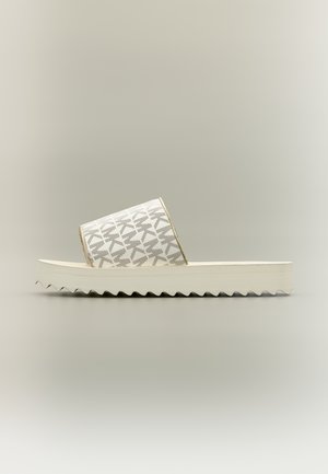 Sandale mule à plateforme blanche avec une large lanière grise à motifs et une semelle striée sur fond neutre.