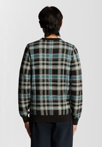 Karierter Pullover mit einem schwarz-weißen und blauen Karomuster, gestricktem Material, gerippten Bündchen und Kragen. Die Ansicht zeigt das Rückendesign.