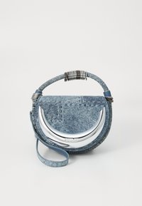 Geantă rotundă din denim cu detalii în formă de semilună din argint, bobine metalice pe mâner și curea de încheiere detașabilă, pe un fundal alb simplu.