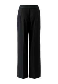 Black wide-leg trousers feature a flat waistband with the text "OUT" embossed. Made from a smooth fabric, they have a relaxed silhouette.