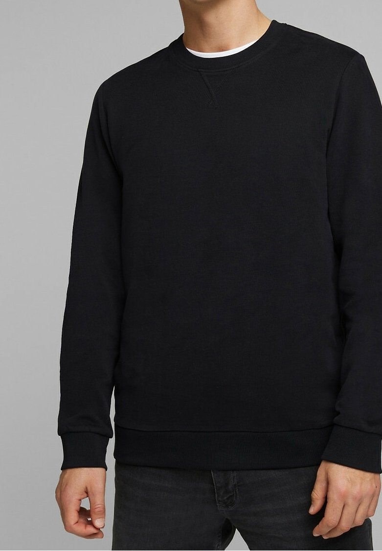 Homme portant un sweat-shirt noir uni à col rond avec poignets et ourlet côtelés, associé à un jean foncé, montré du cou aux hanches.