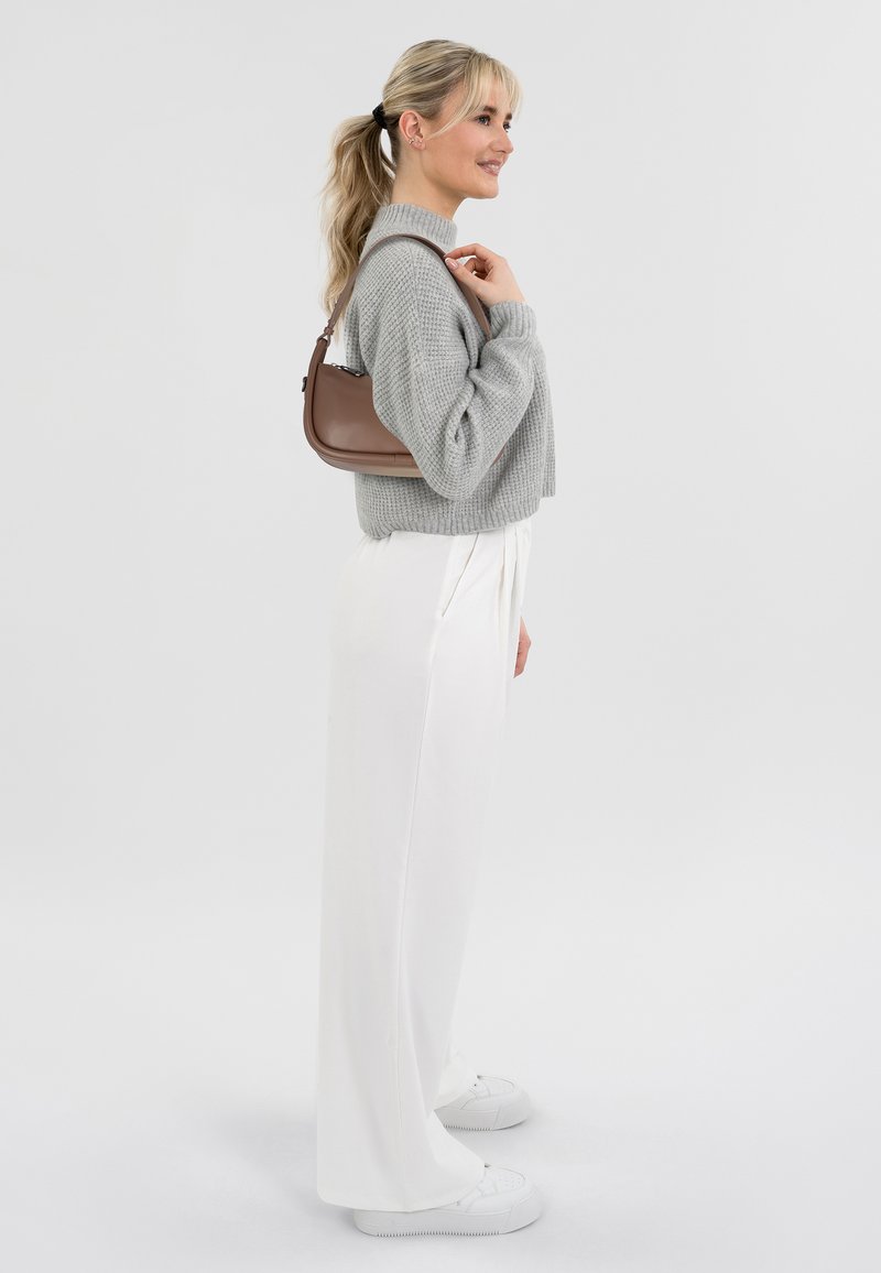 Maglione grigio a maglia, pantaloni bianchi a gamba larga e sneakers bianche. Borsa a tracolla marrone con forma curvata. Texture liscia e design minimalista.