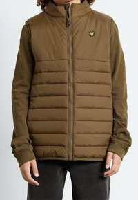 Gilet imbottito di colore verde oliva, con colletto alto, design a quadri verticali, zip frontale e un piccolo logo ricamato sul petto.