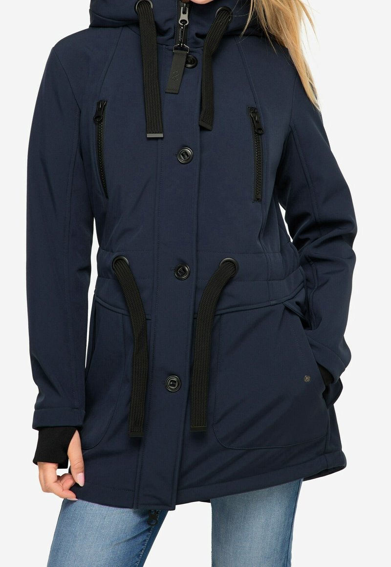 Marinblå parkajakett med dragsko i huva, dragkedjeförsedda bröstfickor och stora framfickor. Har knäppning med knapp och elastiska ärmslut.