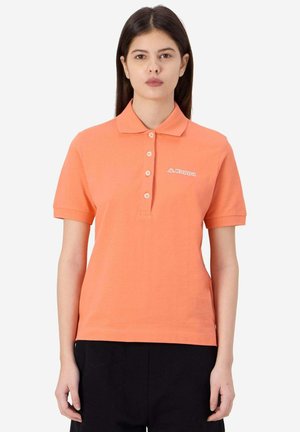 Polo arancione chiaro con colletto, maniche corte e cinque bottoni. Presenta un logo Kappa bianco sul lato sinistro del petto. Texture liscia.
