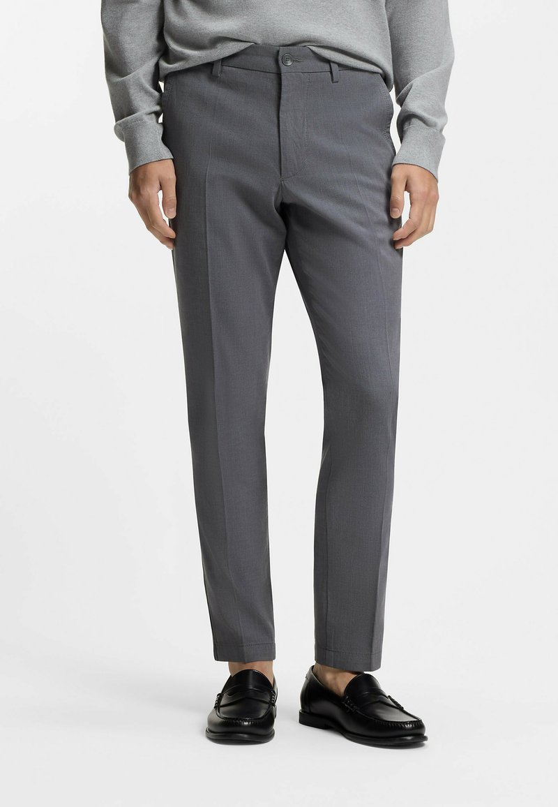 Gray tailored pants with a subtle texture, flat front, and side pockets, paired with black loafers, worn with a gray sweater.