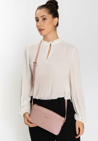 Borsa a tracolla in pelle rosa con finitura testurizzata, strap regolabile e zip dorata. Design semplice con logo sul davanti.