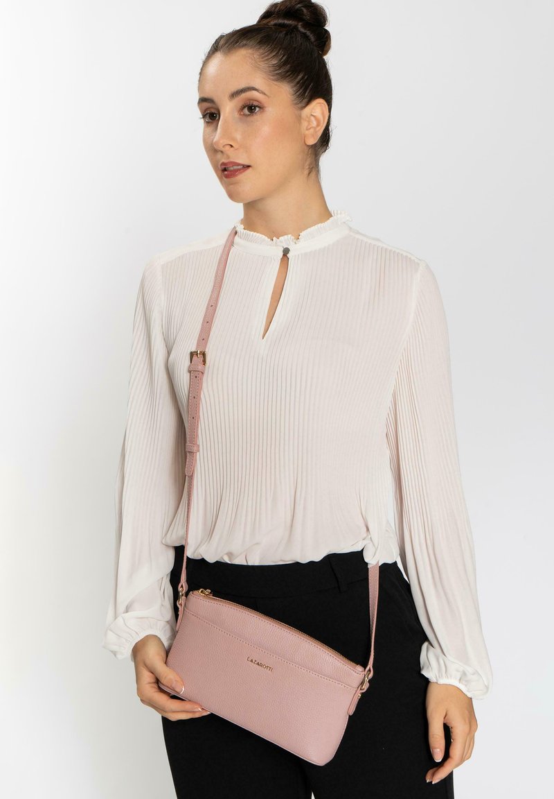 Borsa a tracolla in pelle rosa con finitura testurizzata, strap regolabile e zip dorata. Design semplice con logo sul davanti.