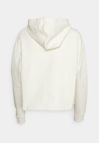Felpa corta color crema con una consistenza morbida, grande cappuccio e spalle scese. Presenta maniche con polsini e un design minimalista.