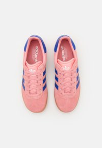 Adidas-sneakers med rosa semsket overdel, blå striper og såle av gummi. Har snøring og merket innersåle.