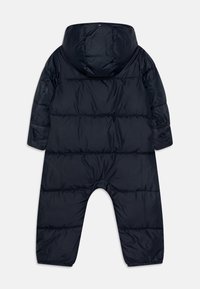 Puffet en-deltants snowsuit i marineblå, med hette, lange ermer og elastiske mansjetter. Glatt nylonmateriale med horisontale sømmer.