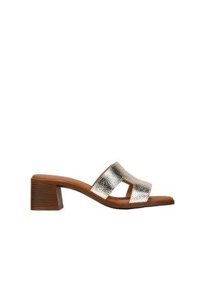 Sandalia de tacón bloque metálico plateado con dos correas anchas y punta abierta. Textura de cuero suave, combinada con una suela marrón.