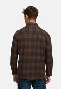 Camicia in flanella a quadri marroni e neri con colletto button-down, maniche lunghe e polsini con bottone, vista da dietro.
