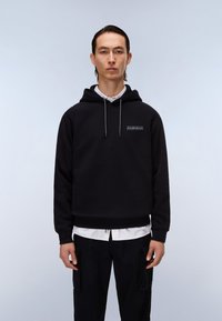 Moleton preto com capuz, featuring um bolso frontal, cordão e detalhe do logótipo. Usado sobre uma camisa branca com colarinho, combinado com calças cargo escuras.