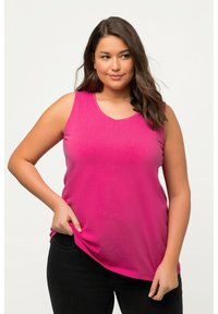 Fuchsia tanktop met een V-hals en mouwloos ontwerp, gemaakt van zachte stof. Gecombineerd met donkere jeans met een ontspannen pasvorm.