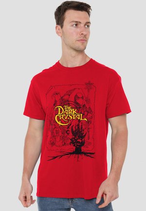 Red cotton t-shirt featuring a black graphic print with characters from "The Dark Crystal" and decorative yellow lettering.