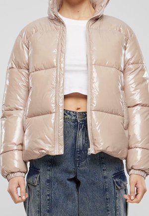 Gevoerde, glanzende beige pufferjack met een capuchon, cropped ontwerp, rits aan de voorkant en elastische manchetten, gecombineerd met high-waisted denim broek.