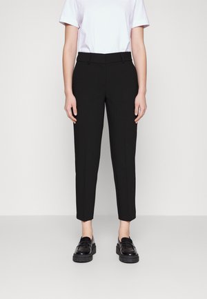 Sorte skreddersydde bukser med slim fit, med flat front, sidelommer, og en cropped lengde. Kombinert med svarte lær loafer.