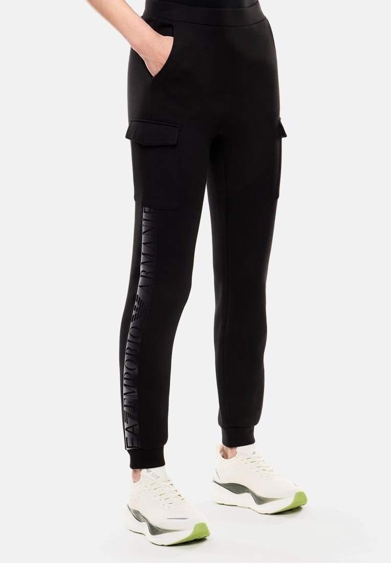 Pantaloni da jogging neri in materiale morbido con tasche laterali, caratterizzati da un logo in rilievo verticale sulla gamba sinistra e caviglie a costine.