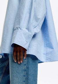 Lichtblauw overhemd met lange mouwen en een knoopmanchet, met een relaxed fit en een soepele textuur, gecombineerd met blauwe denim broek.