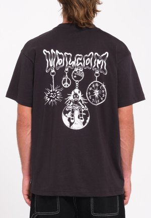 T-shirt en coton noir avec un grand graphisme blanc dans le dos présentant divers motifs, notamment un soleil, une horloge et une poupée. Manches courtes.
