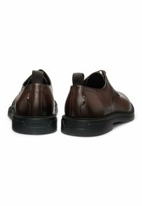 Brązowe skórzane buty o gładkiej fakturze, zaprojektowane z okrągłym noskiem, elastycznymi akcentami i grubą czarną gumową podeszwą.