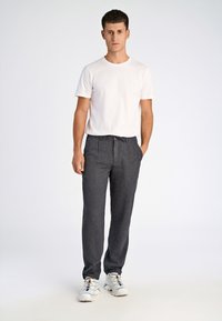 Pantaloni grigi a righe con vita con cordoncino. Abbinati a una t-shirt bianca semplice e sneaker bianche con accenti colorati.
