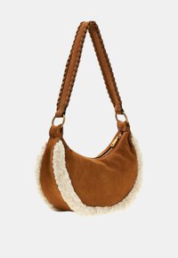 Borsa a spalla in suede marrone con tracolla intrecciata, rifiniture in pelliccia sintetica color crema, forma rotonda e chiusura con zip.