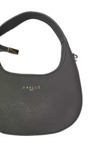 Borsa in pelle grigia con una forma curva, caratterizzata da una superficie liscia e un dettaglio del logo dorato, dotata di un manico corto e chiusura con zip.