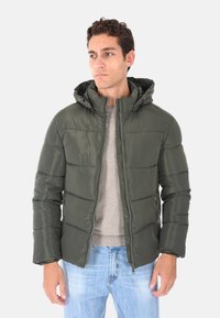 Giacca imbottita verde oliva con cappuccio, chiusura con zip e tasche laterali; presenta una texture trapuntata e un'esterno leggero e lucido.
