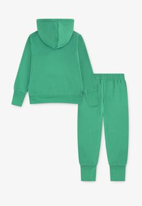 Haut à capuche vert avec long manches, associé à un pantalon de jogging assorti avec des poignets et une taille élastiques. Matière douce et lisse.
