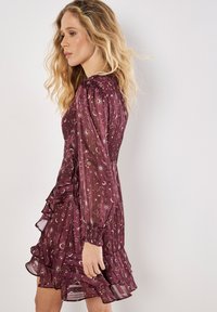 Bordeauxrotes Kleid mit langen gepufften Ärmeln, durchsichtigem Stoff, goldenen Stern- und Mondmustern, einem schulterfreien Saum und einer taillierten Taille für eine formschöne Silhouette.