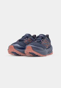 Marine blije hardloopschoenen met roze accenten, dikke zolen, gestructureerd materiaal en een opvallend logo aan de zijkant. Ideaal voor prestaties en comfort.